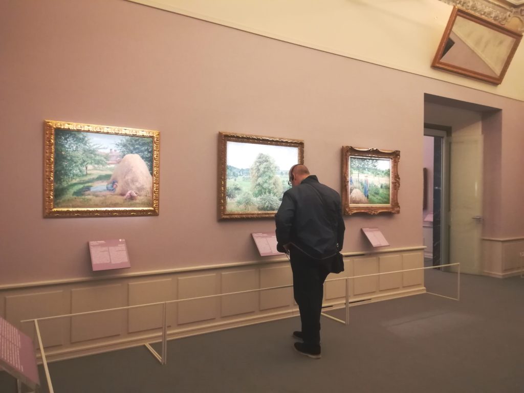 Un visitatore tra le opere di Camille Pissaro esposte a Palazzo Bonaparte